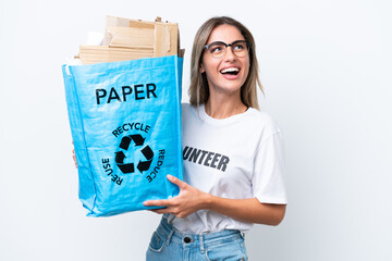 Canvas Print - Young pretty Uruguayan woman holding a recycling bag full of paper to recycle isolated on white chroma background looking up while smiling