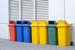 Yellow, green, blue and red recycling bins with separate recycling symbols on the building wall