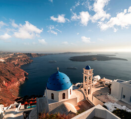 Wall Mural - Golden hour image of white and blue church with view on the caldera cliff and cruise ships on the Greek island of Santorini