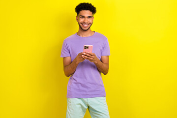 Wall Mural - Photo of positive nice person toothy smile hold use smart phone eshopping chatting isolated on yellow color background