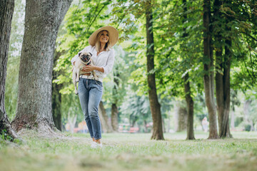 Wall Mural - Woman having a walk in park with her pug-dog pet