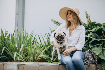 Wall Mural - Woman sitting in park with her pug-dog pet