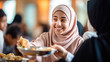 Muslim girl in hijab sharing lunch with friends in school cafeteria