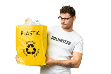 Wall Mural - Brazilian man holding a bag full of plastic bottles to recycle over isolated chroma key background with sad expression