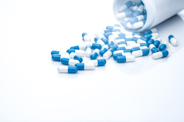 Wall Mural - Blue-white antibiotic capsule pills spread out of plastic drug bottles. Antibiotic drug resistance. Prescription drugs. Healthcare and medicine. Pharmaceutical industry. Pharmacy product. Medication.