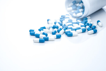 Sticker - Blue-white antibiotic capsule pills spread out of plastic drug bottles. Antibiotic drug resistance. Prescription drugs. Healthcare and medicine. Pharmaceutical industry. Pharmacy product. Medication.