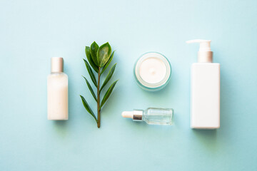Wall Mural - natural cosmetic products. cream, serum, tonic with green leaves. top view on blue background.
