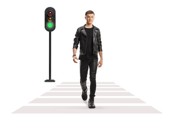Wall Mural - Full length portrait of a guy in a leather jacket and pants walking at pedestrian crosswalk