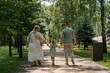 © Guys Who Shoot - Little cute girl in green summer dress with parents in city park on a walk summer family lifestyle Childhood happy family rear view