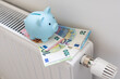 save heating costs, heating radiator with piggy bank, white background