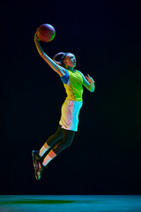 Wall Mural - Slam dunk. Female basketball player in motion, jumping with ball against black studio background in neon light. Concept of professional sport, action and motion, game, competition, hobby, ad