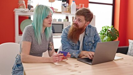 Wall Mural - Man and woman couple sitting on table shopping with laptop and credit card at dinning room