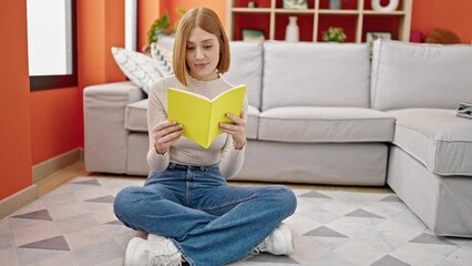 Sticker - Young blonde woman reading book sitting on floor at home