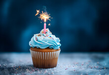 Birthday Cupcake With A Candle And Festive Tinsel Decoration On A Blue Background With Copy Space. Generated AI.