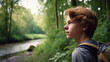 teenager boy going for a walk or hiking and enjoying nature, in the countryside, environment and plants, beautiful day outside, walking through grass on a river at the edge of the forest