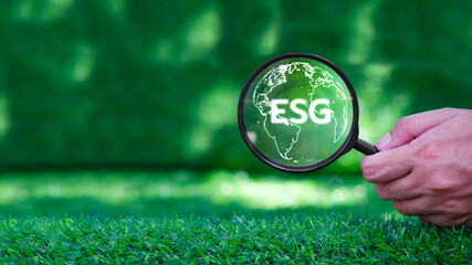 ESG concept of environmental, social and governance. Hand holding magnifying glass with ESG and world eco concept. Earth day.