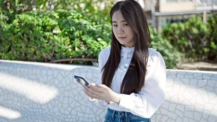 Canvas Print - Young chinese woman using smartphone smiling at park