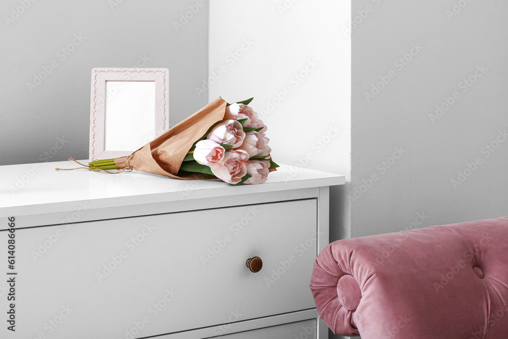 Blank frame and tulips on commode in light room