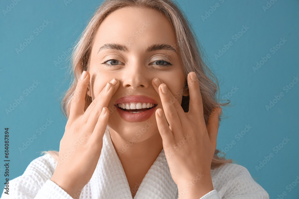 Young woman doing face building exercise on blue background, closeup