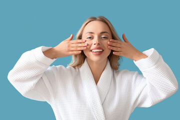 Young woman doing face building exercise on blue background