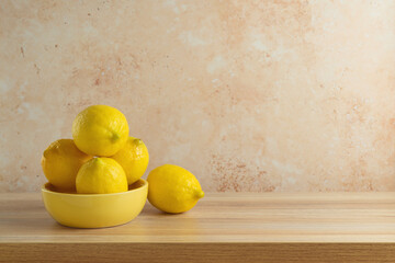 Canvas Print - Lemons in yellow bowl on wooden modern table. Kitchen mock up for design and product display