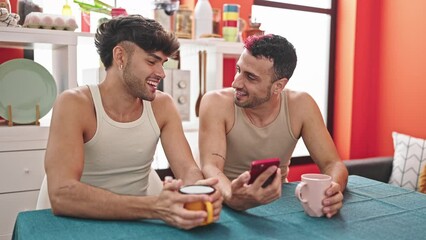 Wall Mural - Two men couple drinking coffee using smartphone at dinning room