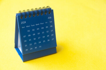 July 2024 blue desk calendar on yellow cover background with customizable space for text. Copy space and calendar concept