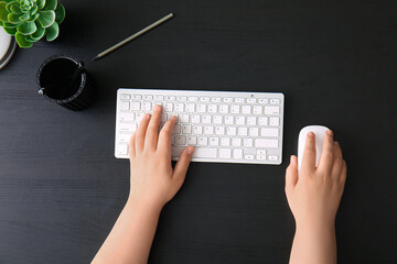 Female programmer using computer keyboard and mouse on dark wooden background