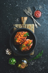 Vegetarian menu. Baked sweet potatoes with spices and garlic in a pan. Healthy food. On a black stone background.