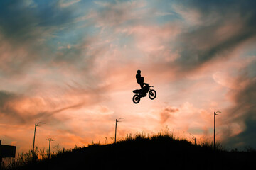 Wall Mural - FMX rider performs dangerous stunts at sunset. Motocross.