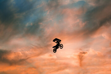 Wall Mural - FMX rider performs dangerous stunts at sunset. Motocross.