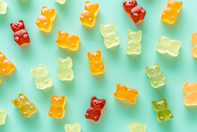 Above view of colorful gummy bears on a flat green background. Creative wallpaper for a candy store with marmalade gummy bears candy. Generative AI professional photo imitation.