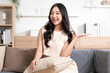 © 220 Selfmade studio - Happy attractive asian young woman smile and open hand palm to copy space at home. Cheerful pretty girl wear casual dress open palm to empty space for mockup to display product