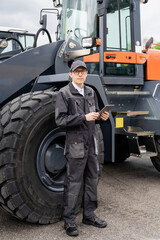 Poster - Man with digital tablet next to industrial tractor.