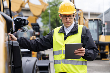 Aufkleber - Worker in a helmet with a digital tablet on the background of construction machine.