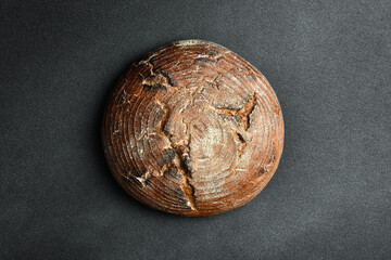 Wall Mural - Homemade black bran round bread. Fresh bread on a black background. Top view.