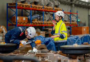 Professional technician or engineer try to check and fix the problem part of electric train and work with factory worker use walkie talkie to contact co-worker team in workplace area.