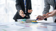 © amnaj - Group of business people working together on new project with planning analytical report at meeting. Businesspeople meeting together pointing to graph assess business profits.