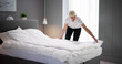 Young Female Housekeeper Changing Bedding