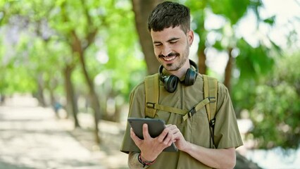 Sticker - Young hispanic man tourist wearing backpack using touchpad at park