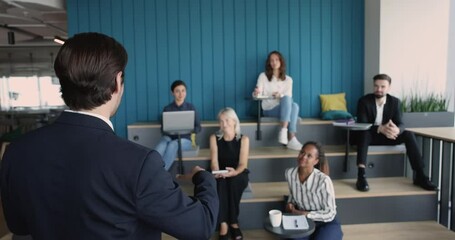 Wall Mural - Back of business leader man speaking to audience, presenting speech, project plan. Corporate coach, teacher, mentor giving training lecture, workshop, teaching team of interns, employees