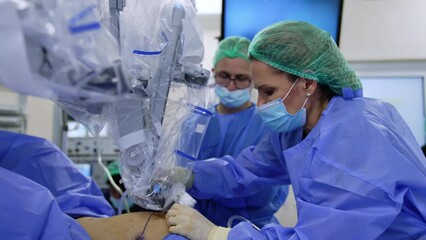 Wall Mural - Female doctor attaches the robotic arm to the incision in patient's belly. Laparoscopy conducted by the Da Vinci robot.