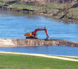 Orange excavator works on the river bank