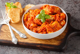 Homemade fish stew with vegetables in spicy tomato sauce served with toast close-up on a wooden board on the table. horizontal