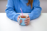 Fototapeta  - Picie ciepłego napoju czarnej herbaty z kubka przez plastikową słomkę