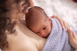 Adorable Newborn Baby Boy sitting on mother chest. Skin to Skin