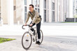 © muse studio - The guy with the business bag uses environmentally friendly transport. A young man riding a bicycle in formal clothes came to work in the office.