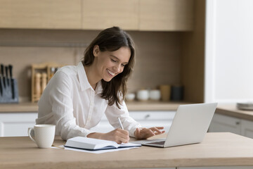 woman write notes, planning workday and meeting in personal paper organizer sit at table with laptop