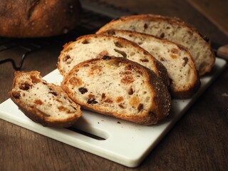 Wall Mural - slice of raisin, cranberry and perilla seed bread on white cutting board