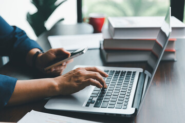 A young female of banking manger using calculator, computer laptop, paper worksheet to analyze data information. She is a professional financial of banking and calculating payment of currency exchange